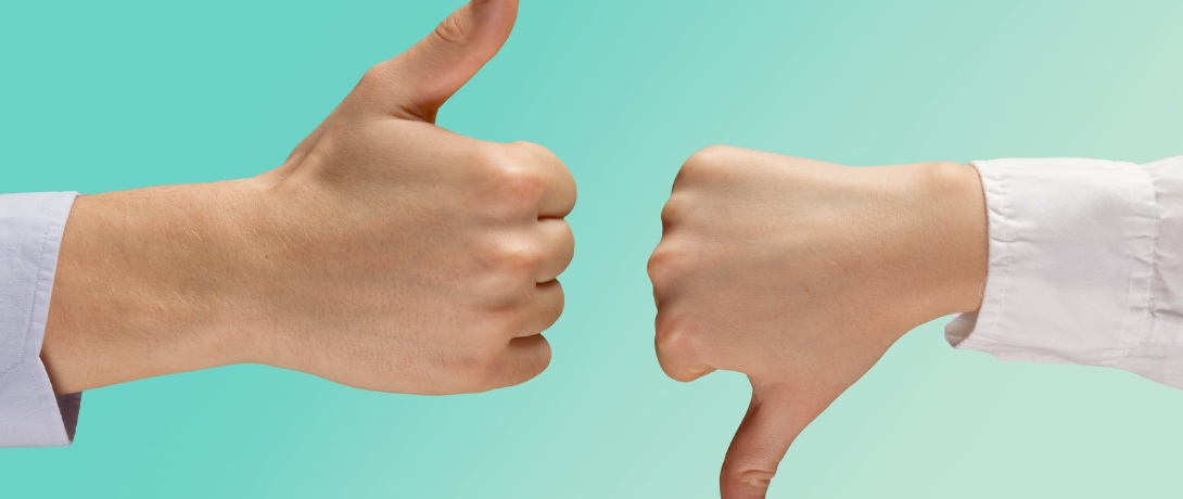 duas mãos frente a frente, uma com o polegar para cima sinalizando aprovação e outra com o polegar para baixo sinalizando reprovação.