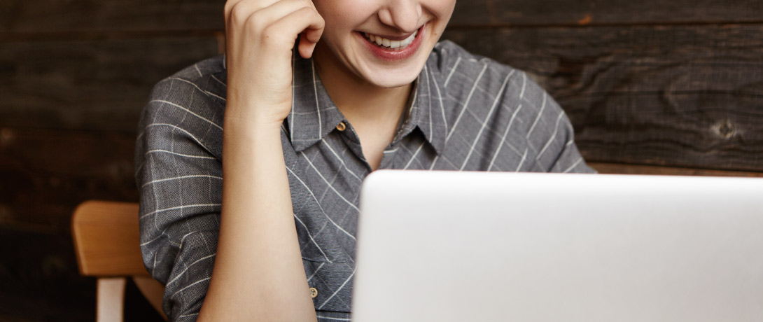 close em pessoa sorrindo enquanto olha para um computador