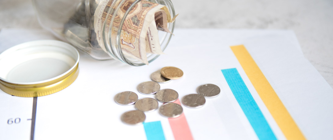 cofrinho de moedas aberto sobre uma folha com gráficos