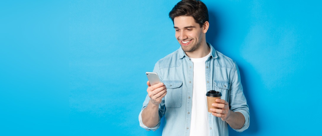 Homem sorri enquanto olha o celular.