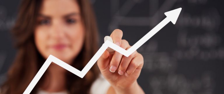 Mulher desenhando gráfico de crescimento com seta para cima, simbolizando sucesso e progresso nos negócios.