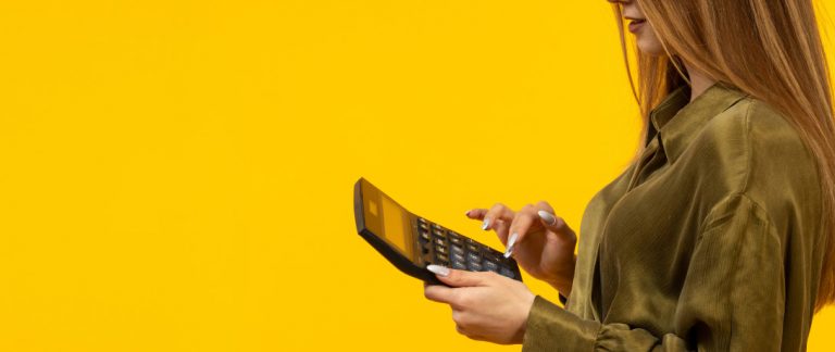 Mulher usando calculadora para organizar finanças, representando o planejamento de pagamentos recorrentes.