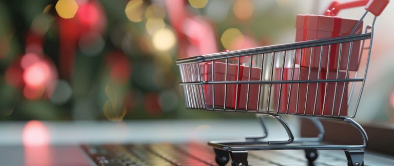 Carrinho de compras com caixas de presente sobre um teclado de notebook, simbolizando aumento das vendas no fim de ano.